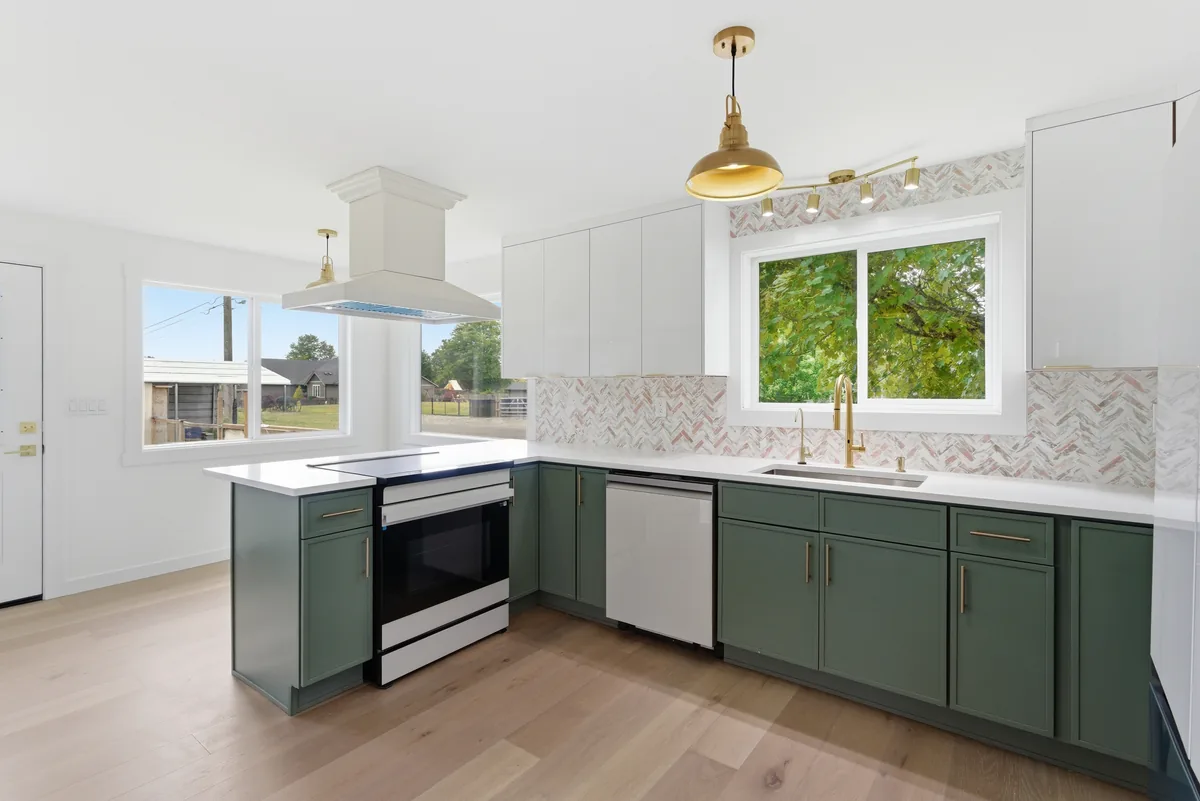 Range wall and hood. Backsplash tile carried the full height to the hood, cuts kept off the sightline.