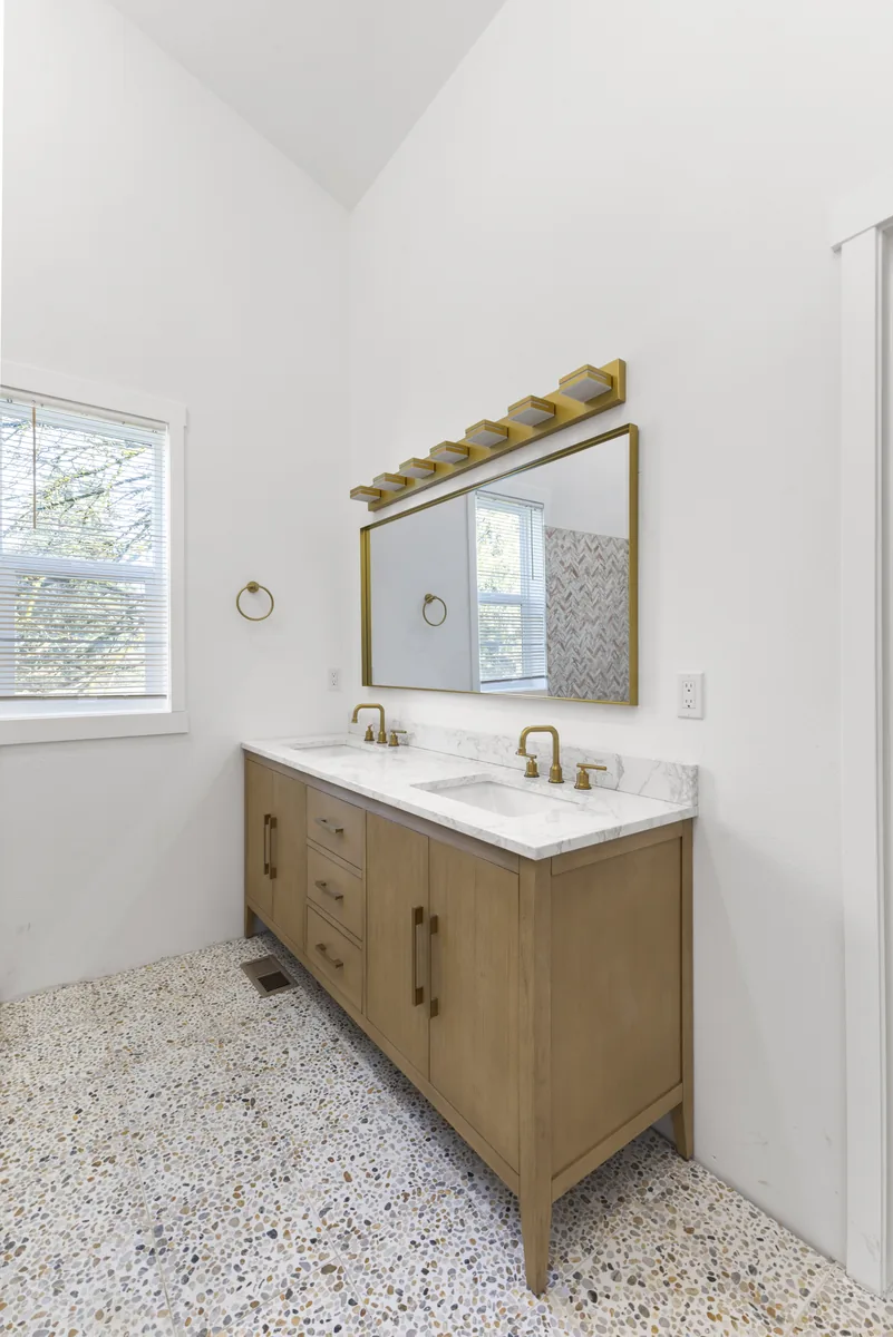 Oak vanity on terrazzo. Terrazzo floor tile set flat and level under a floating oak vanity.