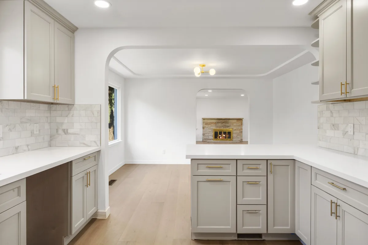 White kitchen, stone backsplash. Full-height stone behind the counter with a waterfall return on the peninsula.
